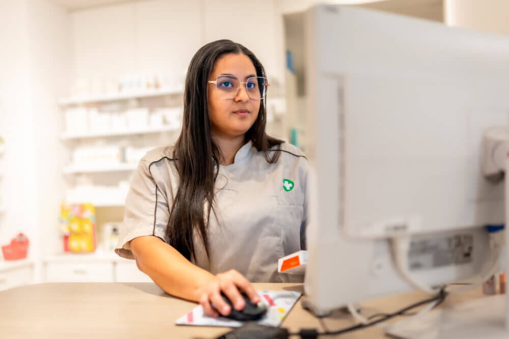 Young female pharmacist checking a product in the computer standing in the counter in the store